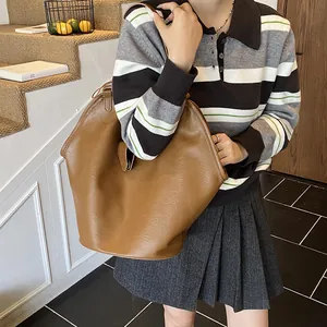 Detailed view of the large brown faux leather tote bag carried over the shoulder