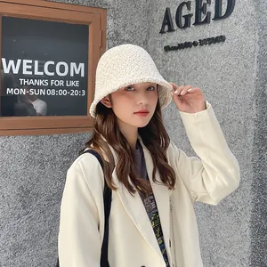 Close-up of a warm beige sherpa bucket hat worn by a model in a stylish street setting