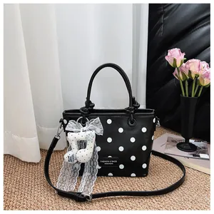 Detail of black and white polka dot handbag with elegant lace musical note pendant