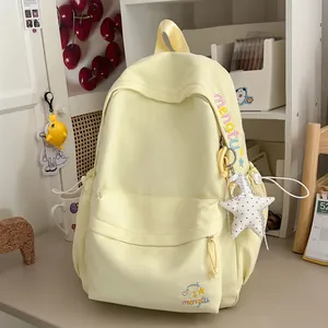 Detailopname van een lichtgele rugzak in Koreaanse stijl met borduursel en een sterhanger.