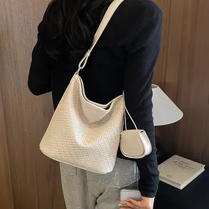 Detail of cream woven hobo bag with mini pouch, styled on model for commuter look.