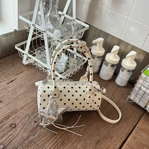 Macro view of white polka dot barrel bag with star pendant on a wooden surface
