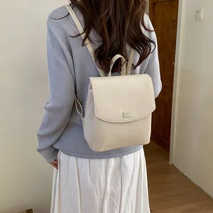 Back view of a woman wearing a stylish minimalist off-white backpack for daily commuting.