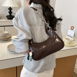Detailed view of dark brown crocodile-patterned hobo bag with colorful bead charm