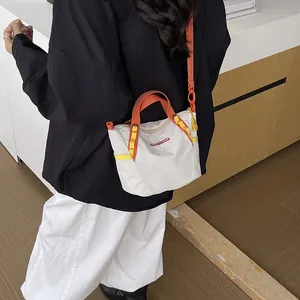 Detail showing an off-white checkered crossbody bag with vibrant orange and yellow straps.