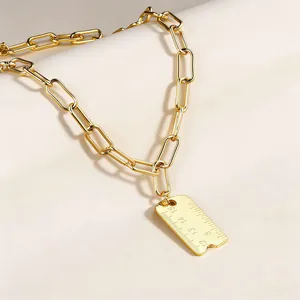 Vue macro d'un collier chaîne trombone doré avec un pendentif créatif en forme de règle