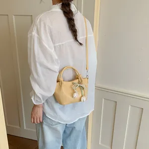 Detailed lifestyle view of a yellow bucket bag with pearl bow and tulip charms on a model