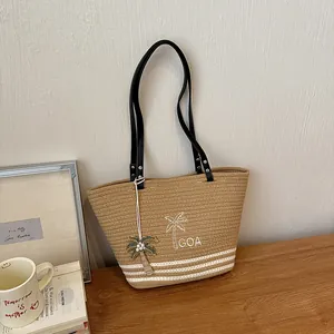 Gewebte Strohtasche mit Palmenstickerei und Anhänger in minimalistischer Umgebung