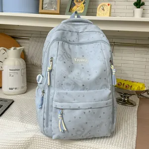 Detail of light blue backpack featuring heart and bow patterns with YOUBAILI brand patch.