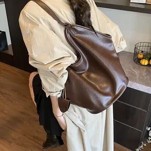 Slouchy large brown leather tote bag shown worn by a model in a lifestyle setting