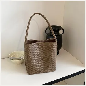 Detalle de un bolso de hombro tipo cubo tejido a mano en un entorno interior minimalista