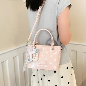 Close-up of a pink polka dot handbag worn by a model as a stylish crossbody bag.