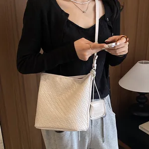 Detailed lifestyle view of a woven white bucket bag worn as a stylish crossbody