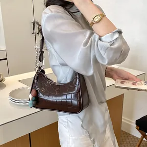 Minimalist dark brown crocodile pattern underarm hobo bag styled in a casual setting
