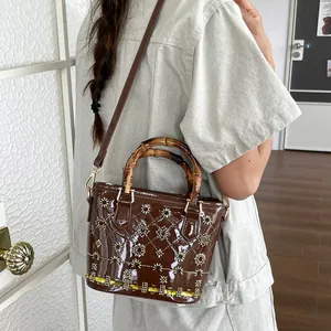 Elegant vintage brown patent leather bucket bag featuring a bamboo handle and floral sequins