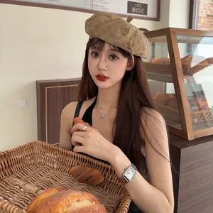 Detail view of a stylish vintage tan beret hat worn by a model in a cozy bakery setting