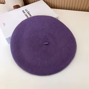 Flat lay detail view of a classic deep purple wool beret hat with a felt texture.