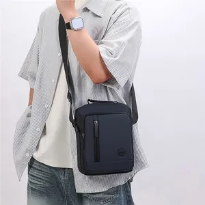 Stylish men's black crossbody messenger bag worn by a model in a casual outfit.
