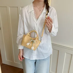 Detailed view of a light yellow bucket bag with pearl bow and tulip charms on a model