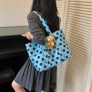 Close-up showing a light blue polka dot tote bag with a cute brown teddy bear charm attached.