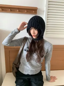Model trägt eine schwarze gestrickte Balaclava-Mütze in gemütlichem Ambiente