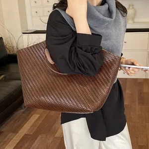 Detailed view of a large brown woven tote bag carried over the shoulder.