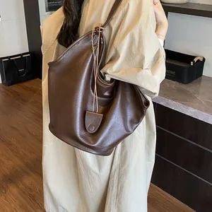Large capacity brown leather hobo tote bag shown on model in a stylish interior setting