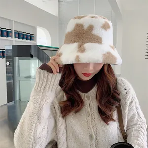 Close-up detail of a soft plush cow print bucket hat worn by a model in a cozy cafe setting