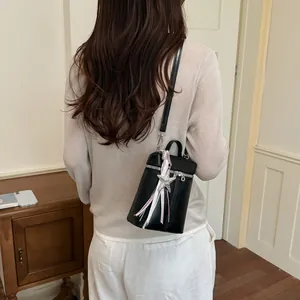 Borsa a tracolla nera minimalista con ciondolo a stella indossata da una modella in un interno
