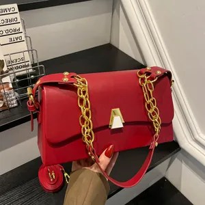 Detailed view of stylish red square handbag with elegant gold chain and geometric clasp.