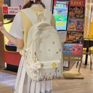 Primo piano di uno zaino in tela bianca con ricami floreali colorati in un caffè (85)