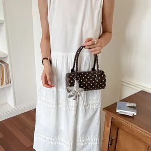 Stylish brown cylindrical handbag with blue polka dots and silver star charm detail