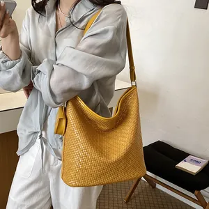 Stylish yellow woven shoulder bucket bag worn by a model in a lifestyle setting