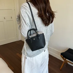 Petit sac seau en cuir noir avec doublure rayée, présenté porté par un mannequin de dos
