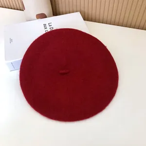 Close-up detail of a classic burgundy wool beret with soft felt texture for autumn winter style.