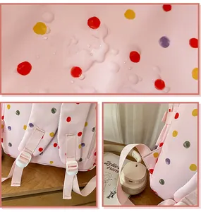 Dettaglio tessuto rosa impermeabile con pois colorati e spallacci dello zaino regolabili.