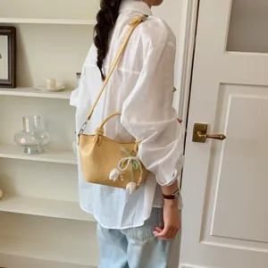 Elegant yellow bucket shoulder bag with tulip and pearl charms worn with white shirt