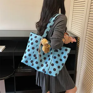 Detail view of a stylish light blue polka dot tote bag featuring a cute teddy bear charm.