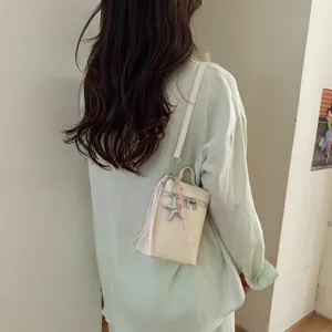 Vista posteriore di una donna con una borsa porta cellulare beige e ciondolo a stella