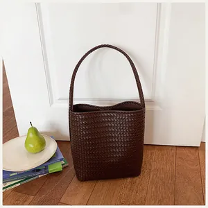 Detalle de un bolso bombonera trenzado marrón en un entorno de hogar minimalista.