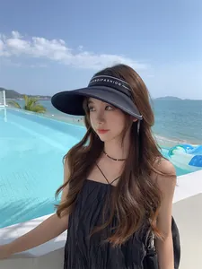 Vue détaillée d'un chapeau visière solaire noir à large bord porté par un mannequin.