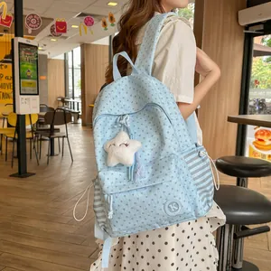 Light blue school backpack with star pattern and plush star pendant in a cafe setting