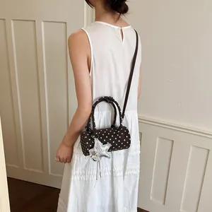 Detailed view of a small polka dot cylindrical handbag with a silver star charm