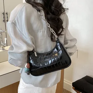 Close-up of a black crocodile-patterned crescent hobo bag worn by a model.