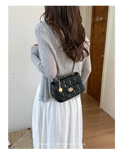 Zwarte gewatteerde ketting crossbodytas met retro draaisluiting, getoond op de rug van het model.
