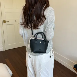 Vue de dos d'une femme portant un petit sac seau noir avec cordon à rayures