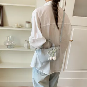 Elegant back view of model carrying a light blue bucket bag with pearl tulip bow detail
