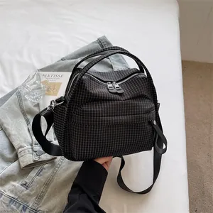 Nahaufnahme des karierten Stoffes und der Doppelreißverschlüsse der schwarzen Tasche.