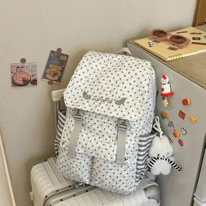 Close-up of star pattern backpack with plush bear charm sitting on a silver suitcase