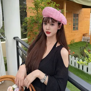 Close-up view of a stylish pink frayed edge beret hat worn by a model in a garden